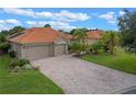 Beautiful house with a brick driveway, two-car garage, terra cotta roof, and lush landscaping with mature palms at 133 Torino Ln, Kissimmee, FL 34759