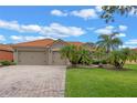 Charming house with a brick driveway, two-car garage, terra cotta roof, and lush landscaping with mature palms at 133 Torino Ln, Kissimmee, FL 34759