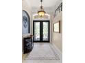 Elegant foyer with tile flooring, decorative light fixture, and glass paneled doors at 133 Torino Ln, Kissimmee, FL 34759
