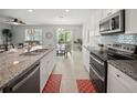 Open kitchen with modern appliances, granite countertops, island with seating, and access to the living and dining area at 1809 Bluepoint St, St Cloud, FL 34771