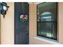 Exterior view of a front door with floral wreath and black trim near a window with blinds at 1825 Pelican Hill Way, Kissimmee, FL 34759