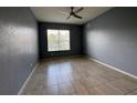 An empty bedroom featuring a window, ceiling fan, and neutral walls with tile flooring at 3321 Whitestone Cir # 204, Kissimmee, FL 34741