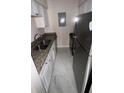A galley kitchen features stainless steel appliances, granite countertops, and marble tile flooring at 7341 Daniel Webster Dr # 4, Winter Park, FL 32792