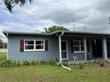 Close up of charming one-story home with covered entry and red shutters at 921 Louisiana Ave, St Cloud, FL 34769