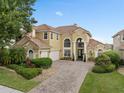 Elegant two-story home with a tile roof, arched windows, and a paver driveway at 2234 Callaway Ct, Davenport, FL 33837