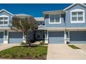 Charming two-story townhouse with light blue exterior, featuring attached garages and lush landscaping in front at 4525 Sw 52Nd Cir # 103, Ocala, FL 34474