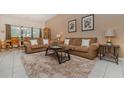 Spacious living room with plush seating, neutral decor, and tile flooring throughout at 7719 Comrow St, Kissimmee, FL 34747