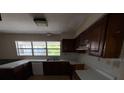 Outdated kitchen featuring wooden cabinets, laminate countertop, a window, and standard appliances at 8 Emerald Way, Ocala, FL 34472