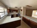 Outdated kitchen with brown wooden cabinetry and a laminate countertop; view to another room at 8 Emerald Way, Ocala, FL 34472