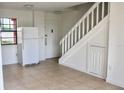 Bright entryway with neutral tile floors, a white refrigerator, and staircase leading to the upper level at 10330 Turkey Lake Rd # A-4 Ak/A 107, Orlando, FL 32819