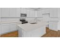 Modern kitchen featuring white cabinets, stainless steel appliances, and an island at 1126 Olivine Ave, Dundee, FL 33838