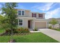 Attractive two-story home with a well-maintained lawn, an attached garage, and a welcoming front entrance at 1650 Sugarbelle Cir, Mascotte, FL 34753