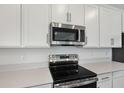 Close-up highlighting stainless steel oven, microwave, white cabinets, and countertops in a modern kitchen at 1650 Sugarbelle Cir, Mascotte, FL 34753