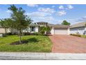 Charming single-story home with lush lawn, mature trees, and a brick driveway on a sunny day at 789 Cielo Trl, Kissimmee, FL 34759