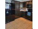 The kitchen has black appliances, plenty of counter space, and stylish brown backsplash at 13 Dorset Dr, Kissimmee, FL 34758