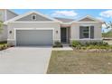 Inviting single-story home with a two-car garage, stone accents, and manicured lawn at 1654 Sugarbelle Cir, Mascotte, FL 34753