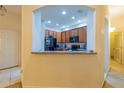 A view of the kitchen featuring wood cabinets, black appliances, and granite countertops, seen through an arched opening at 3301 Whitestone Cir # 203, Kissimmee, FL 34741