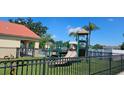 Community playground with modern equipment, lush green turf and black metal fencing surrounding the play area at 2804 Club Cortile Cir # A, Kissimmee, FL 34746