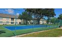 Bright blue and green community tennis court surrounded by a tall chain link fence and mature landscaping at 2804 Club Cortile Cir # A, Kissimmee, FL 34746