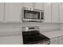 Close up of modern stainless steel microwave and stovetop with white countertops at 317 Alexandrite St, Deland, FL 32720