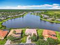 Beautiful aerial view of a lakefront home with lush green lawn, terracotta roof, and access to community amenities at 644 Shorehaven Dr, Kissimmee, FL 34759
