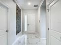 Bright entryway with marble tile floors, white door, and modern decor at 1326 Butterfly Orchid Rd, Davenport, FL 33837