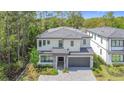 Elegant two-story home boasts mature trees, a gray tile roof, a stone-accented entrance, and a two-car garage at 1326 Butterfly Orchid Rd, Davenport, FL 33837
