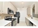 Compact kitchen with neutral tone cabinets, modern appliances, and a decorative backsplash at 1357 Venezia Ct # 202, Davenport, FL 33896