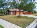 View of the home's driveway and three-car garage, complemented by green grass and landscaping at 20249 Macon Pkwy, Orlando, FL 32833