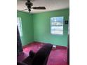 Bedroom with two windows, green walls, and stained red carpet at 2117 Lemon St, Haines City, FL 33844