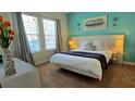 Bright bedroom featuring a queen-sized bed with a white comforter and teal accent wall, illuminated by natural light at 228 Captiva Dr, Davenport, FL 33896