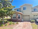 Inviting two-story townhome featuring stone accents, a one-car garage, and a brick-paved driveway at 2305 Chatham Place Dr, Orlando, FL 32824
