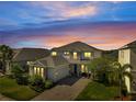 Charming two-story home featuring stone accents, a spacious garage, and a beautifully paved driveway at dusk at 2348 Pearl Cider St, Orlando, FL 32824