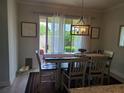 Bright dining room area features a modern chandelier, laminate flooring, and sliding glass doors to the backyard at 2522 Nouveau Way, Kissimmee, FL 34741