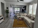 Open-concept living room boasts a large sectional couch and modern decor, seamlessly connecting to the dining area at 2522 Nouveau Way, Kissimmee, FL 34741