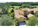 Aerial view of a yellow home with a brown roof, featuring a two-car garage and landscaped surroundings at 2724 Palm Tree Dr, Poinciana, FL 34759