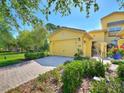 Charming yellow home features a brick driveway, well-manicured landscaping, and a two-car garage at 2724 Palm Tree Dr, Poinciana, FL 34759