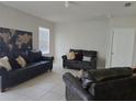Living room featuring neutral colors, tile floors, and comfortable leather sofas at 320 Aberdeen Dr, Davenport, FL 33896