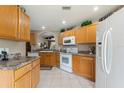 The kitchen features wood cabinets, white appliances, ample counter space and tile flooring at 801 Ashton Dr, Davenport, FL 33837