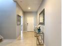 Light and bright entryway with neutral tile flooring, modern mirror, and a glass console table with decorative orchids at 8039 Oak Shadow Ct, Davenport, FL 33837