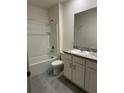 Bathroom features a shower-tub combo, toilet, granite countertop vanity, and grey tile flooring at 167 Eagleview Loop, Davenport, FL 33837