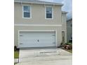 A modern home showcasing a white garage door against a light beige exterior, featuring well-placed windows at 167 Eagleview Loop, Davenport, FL 33837