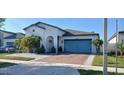 Inviting single-story home with a blue garage door, brick driveway, and tropical landscaping at 2950 Scarlett Dr, St Cloud, FL 34772