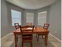 Cozy dining room with wood table, four chairs and natural light coming from three windows at 3105 Sangria St, Kissimmee, FL 34744