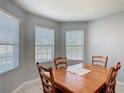 Cozy dining room with wood table, four chairs and natural light coming from three windows at 3105 Sangria St, Kissimmee, FL 34744