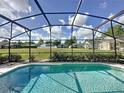 Screened-in pool with clear blue water and views of green backyard, perfect for entertaining at 334 Grosvenor Loop, Davenport, FL 33897