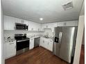 Modern kitchen with stainless steel appliances, white cabinets, quartz countertops, and wood grain floors at 3815 Nw Avenue R Ave, Winter Haven, FL 33881