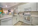 Modern kitchen with white cabinets, countertops, and appliances, plus stylish pendant lighting at 702 Gran Bahama Blvd, Davenport, FL 33897