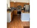 Functional kitchen featuring stainless steel appliances, warm wood cabinetry and hardwood floors at 804 Carrousel Ln, Kissimmee, FL 34759