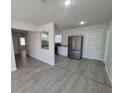 Open-concept living area flows into kitchen with modern stainless steel appliances and gray vinyl flooring at 139 Arroyo Pkwy, Ormond Beach, FL 32174